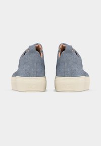 Ζευγάρι αθλητικών παπουτσιών με υφή denim, με μπεζ λαστιχένιες σόλες και λογότυπο «AGL» ανάγλυφο στη φτέρνα, από πίσω σε απλό φόντο.