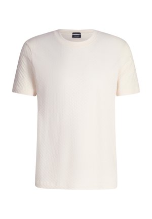 T-shirt à manches courtes de couleur crème avec un motif texturé, col rond et coupe décontractée. L'étiquette est positionnée au niveau du cou.