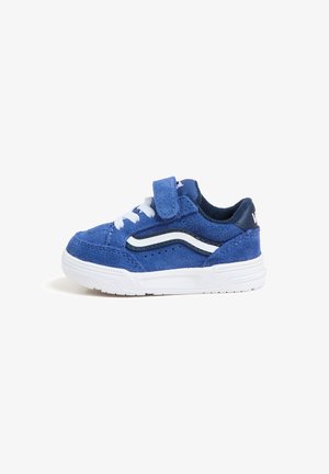 Blå ruskinds sneakers med hvide snørebånd og velcrorem. Har et hvidt bølgemønster på siden og en struktureret sål for godt greb.