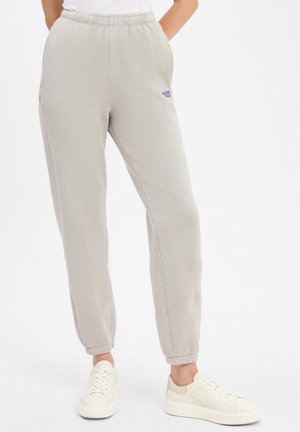 Lichtgrijze sweatpants met een elastische tailleband, zijzakken, ribgebreide boorden en een klein blauw logo-detail. Katoenen mix stof, gladde textuur.