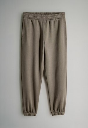 Taubefarbene Sweatpants mit elastischem Bund und Bündchen, ausgestattet mit Seitentaschen, vor einem schlichten hellen Hintergrund präsentiert.