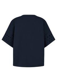 Námořnická modrá oversized tričko s krátkým rukávem, které má výřezy podél okrajů rukávů. Hladká látka s pohodlným střihem.