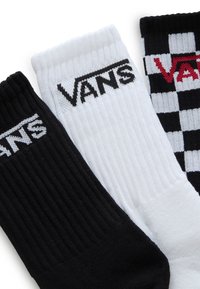 Tres pares de calcetines: negro, blanco y un patrón de tablero de ajedrez. Cada uno tiene el logo de "VANS", textura acanalada y diseños variados.