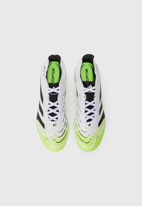 White and black soccer cleats with a textured upper, featuring green accents and three black stripes. Laces on front with a padded collar.