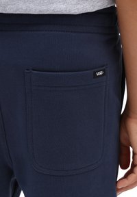 Marineblaue Jogginghosen aus weichem Stoff mit einer großen Gesäßtasche und einem schwarzen Vans-Logo-Tag. Auffällige Nahtdetailing um die Tasche.
