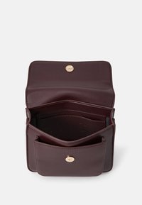 Burgunderfarget lærhåndveske med en strukturert design, som har gullknapplukking og to rom for organisering.