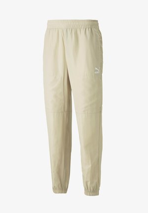 Helle beigefarbene Sporthose aus glattem, leichtem Stoff. Mit elastischem Bund und weißem Logo nahe der linken Hüfte. Mit schmal zulaufendem Bein und elastischen Bündchen.