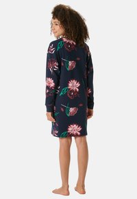Granatowa sukienka w kwiatowy wzór z długimi rękawami, okrągłym dekoltem i luźnym krojem. Materiał ozdobiony jest kwiatami w odcieniach różu i zieleni.