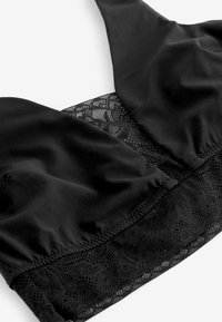 Reggiseno nero con parte superiore in satin liscio e un sotto in pizzo decorativo, caratterizzato da motivi intricati e una texture morbida.