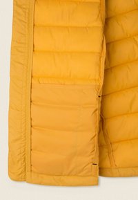 Żółta kurtka puchowa z pikowanym wzorem, z poziomym przeszyciem, bocznymi kieszeniami i gładkim, błyszczącym wykończeniem.