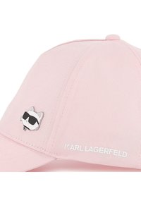 Ροζ καπέλο μπέιζμπολ από υφήλιο ύφασμα, με ασημένια καρφίτσα γάτας με γυαλιά ηλίου και λευκό κείμενο "KARL LAGERFELD" στο πλάι.