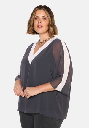 Locker sitzende graue Bluse mit V-Ausschnitt und kontrastierenden weißen Schulterstreifen. Hergestellt aus leichtem Stoff mit durchsichtigen Ärmeln.