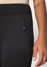 Svarta träningbyxor med en elegant design, utrustade med en ficka med dragkedja, mjuk textur och ett elastiskt midjeband för komfort.