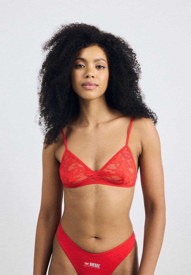 Rode kant bralette met dunne bandjes en een driehoekige vorm, gecombineerd met een bijpassende rode slip met een logo-accent op de tailleband.
