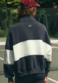 Üks suur pullover tumesinisest ja heledast hallist, millel on kõrge krae, soonilised mansetid ja kaela taga "self." logo. Puuvilla segu materjal.
