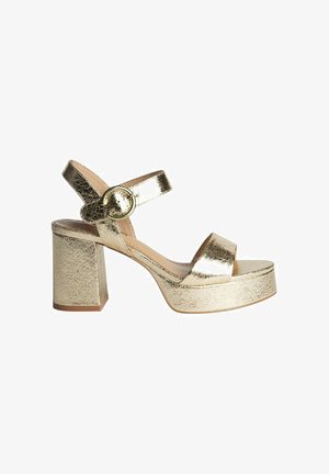 Sandalias de plataforma metálicas doradas con tacón bloque, que cuentan con una correa para el tobillo y una hebilla redonda. Textura suave, diseño de punta abierta.