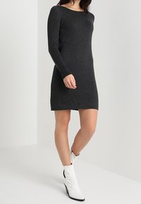 Abito maglione nero a maniche lunghe realizzato in un morbido tessuto testurizzato. Silhouette aderente con scollo rotondo e lunghezza fino a metà coscia.