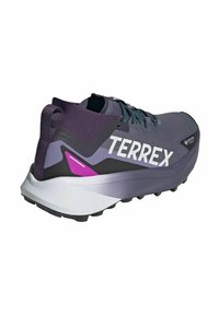 Scarpa da trail running da uomo grigia con superficie texturizzata, dettagli in viola, marchio "TERREX" e suola bianca imbottita con lobi di aderenza.