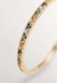 Pulsera de oro con una fila de piedras preciosas multicolores, que incluyen verde, azul, rosa y amarillo, engastadas en configuraciones similares a garras.