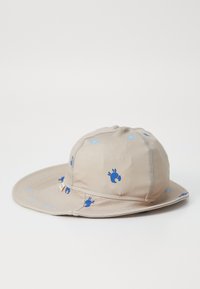 Beige bucket-hatt av lättviktsmaterial med mönster av blå krabbor. Rundad krona med en bred, mjuk skärm och sömnadsdetaljer.