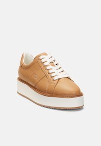 Bruna lädersneakers med vita snören, plattformssula och sömmade detaljer. Har en rundad tå och en texturerad gummiyttersula.