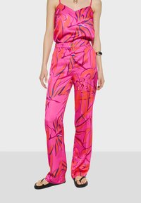 Roze satijnen camisole en bijpassende broek met een levendig bloemmotief in oranje en blauw, met een ontspannen pasvorm en hoge taille.