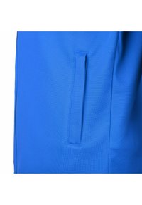 Blå idrottsbyxor med en slät tygtextur, sidoficka med ett snittöppning och en skräddarsydd passform som är utformad för komfort.