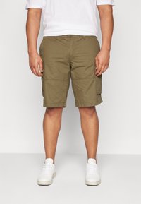 Olivgröna cargoshorts med avslappnad passform, flera fickor och rak fåll. Bärs med en vit T-shirt och vita sneakers.