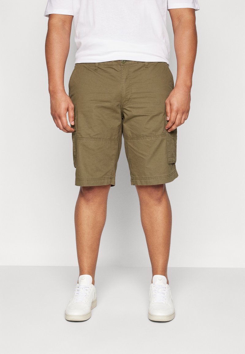 Olivgröna cargoshorts med avslappnad passform, flera fickor och rak fåll. Bärs med en vit T-shirt och vita sneakers.