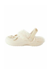 Clogs mit Kunstfellfutter in Cremefarbe, mit dekorativen Schleifen und einem Riemen hinten für sicheren Halt. Texturierte Sohle für besseren Halt.