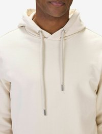 Beige hoodie med dragsko kapuschong, med silverfärgade öglor och randiga metalltips på dragskorna. Mjuk tygtextur.