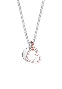 Zilveren ketting met twee hangers: een glanzende ronde schijf en een roségouden hartomtrek, beide bevestigd met een soepele lus.