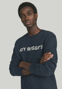 Felpa blu navy in cotone, con colletto a girocollo, polsini a costine e la scritta "ROY ROGER'S" in bianco sulla parte frontale.