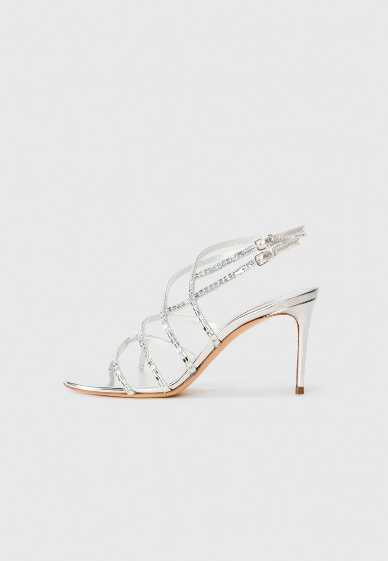 Metallisch silberner High-Heel-Sandaletten mit gekreuzten Riemen, transparenten Akzenten und einem schlanken, spitzen Zehendesign. Verstellbare Knöchellasche.
