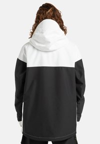 Zwart-witte windbreaker jas met capuchon, met een kleurblokontwerp, contrasterende kleuren op de schouders en elastische manchetten.