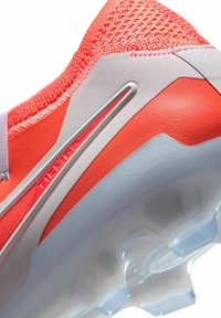 Felrood voetbalschoen met een gestructureerde brei-oberlaag, gladde synthetische accenten en een doorschijnende zool met noppen voor grip.