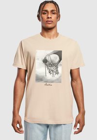 Beige bomulds t-shirt med et sort-hvidt grafisk motiv af en basketballkurv, med teksten "Ballin'" under billedet.