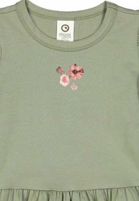 Puuvillamekko salvianvihreänä, jossa on pyöreä pääntie. Koristeena on kukkakirjontaa vaaleanpunaisella ja beigeillä väreillä. Mekon alaosassa on frillapäättely.