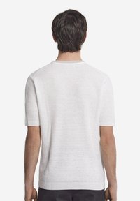 Kortärmad vit stickad tröja med ett texturerat mönster, rund halsringning och ribbade muddarna. Enkelt och lätt design.