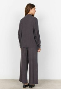 Dunkelgraues Loungewear-Set mit einem lockeren Oberteil mit hohem Kragen und weit geschnittenen Hosen, aus weichem, strukturiertem Stoff.