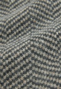 Houndstooth fabric in black, white, and grey tones, featuring a textured, wool-like finish with visible fibers and a diagonal pattern.