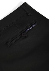 Svarta byxor med en slät tygkvalitet, bakficka med knapp och en etikett med texten "POLO CLUB" i vitt på en marinblå bakgrund.