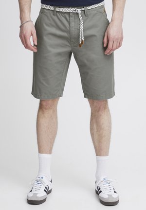 Shorts gris clair à coupe décontractée, avec un cordon de serrage tressé noir et blanc, des poches avant et des bords propres.
