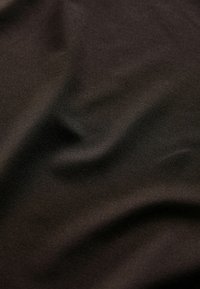 Close-up of dark brown fabric with fine weave texture and soft folds creating subtle shadows and highlights.
