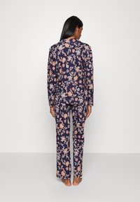 Marinblå lounge-set med blommönster i livfulla orange och rosa nyanser. Inkluderar en långärmad topp och matchande byxor, båda i avslappnad passform.