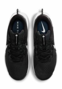 Scarpe da ginnastica nere con tomaia in mesh, suola bianca e dettagli in pizzo testurizzati. Presenta il logo "Nike" sulla soletta e un'etichetta con il marchio sul tallone.