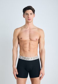 Fekete boxer alsónadrág puha, széles rugalmas derékkal, arany színű "Calvin Klein" logóval. Simaság és testhezálló dizájn.