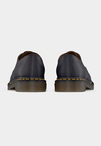 Juodi odiniai batai su apvalia nugarėle, geltonais siūlais palei pado kraštą ir tekstūruotais, sluoksniuotais guminiais padų. Paprastas dizainas, be puošmenų.