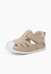 Sandalo in pelle tan con design a intaglio, cinturino in velcro, parao in gomma bianca e suola bianca. Presenta un leggero ammortizzamento per il comfort.