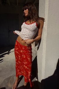 White tank top with floral pattern and red trim, paired with a red floral skirt, showcasing a fitted silhouette and smooth texture.